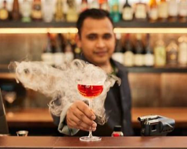 A bartender offers a smoking cocktail.