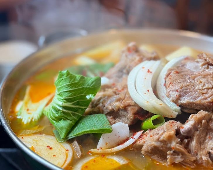 Steaming pot of pork backbone soup with potatoes.