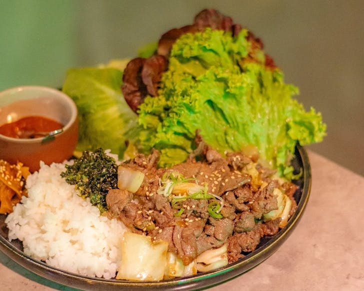 Dish of bulgogi beef with lettuce, rice, kimchi and ssamjang sauce.