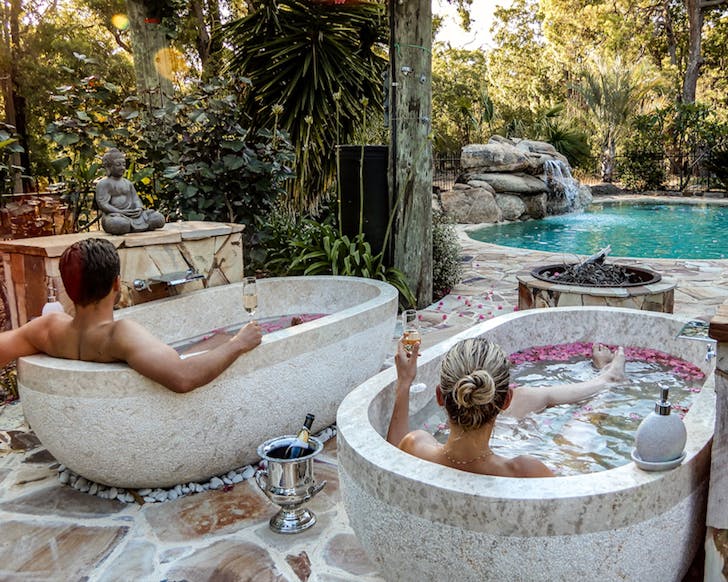 Two people relaxing in outdoor tubs