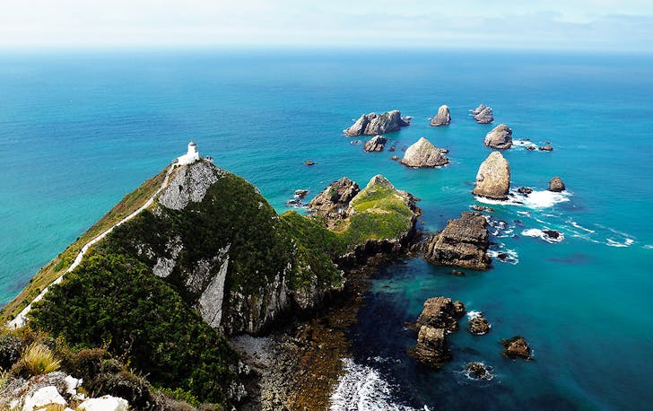 The islands at Nugget Point, New Zealand in the distance under an impossibly sunny day.
