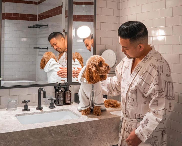A person with their dog in the bathroom at Kimpton Margot, one of the best pet friendly hotels in Sydney