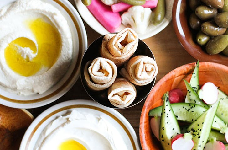 A table with different dips, salads, and pita, a contender for the best middle eastern restaurant Melbourne. 